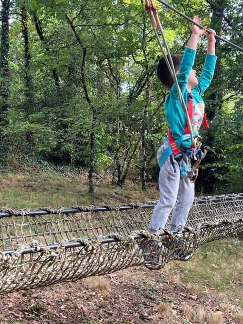 Enfant sur un parcours aventure en pleine nature pendant un séjour en gîte en Dordogne