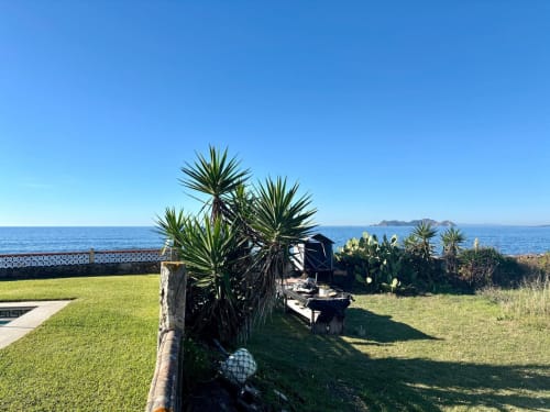 Jardín junto al mar de Baiona con palmeras, vista al océano y terraza de la casita Holibai Albatros