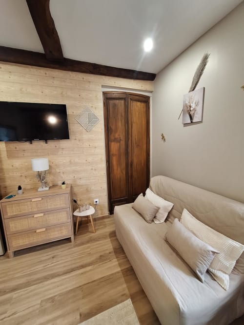 Chambre douillette à La Cour d'Hortense avec canapé crème, boiseries, TV et vue sur le jardin à Sailly-Flibeaucourt