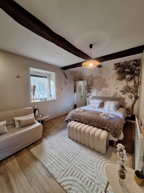 Chambre élégante à La Cour d'Hortense avec poutres apparentes, vue jardin et fresque murale aux tons sépia