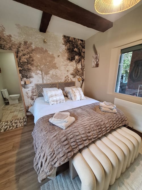Chambre à La Cour d'Hortense avec papier peint forêt, poutres foncées et fenêtre vue jardin