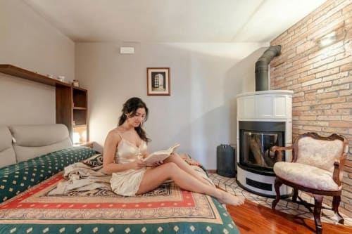 Donna che legge nella accogliente camera da letto di Casa Meravigliosa a Fontanafredda, con camino e muri in laterizio