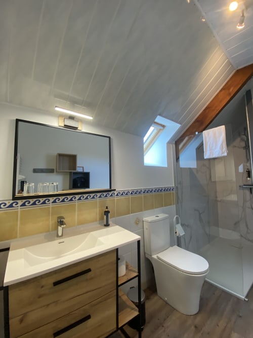 Modern bathroom in Domaine des Piéris BnB with wooden vanity, white fixtures, mirror, and shower