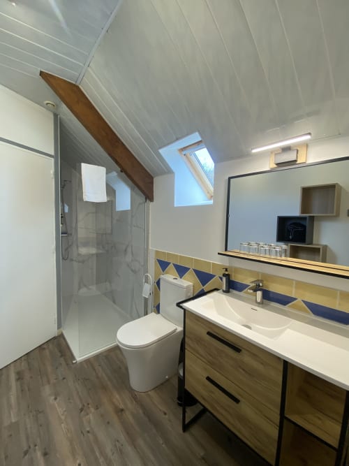 Modern bathroom with shower, toilet, and wooden vanity at Domaine des Piéris B&B in Grandcamp-Maisy, France