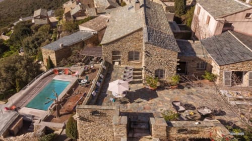 Vue aérienne de La Conciergerie du Cap Corse avec piscine, bâtiments en pierre et terrasse à Centuri