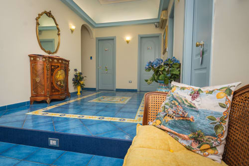 Hall d'ingresso di Casa Mannini B&B a Maiori con pavimenti in piastrelle blu, arredi raffinati e ortensie