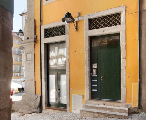 Entrada do hotel PortoSense com fachada amarela e portas verdes no histórico bairro da Ribeira do Porto