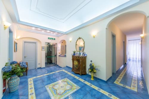 Elegante hall del Casa Mannini B&B a Maiori con pavimenti in piastrelle blu, archi decorativi e arredi raffinati