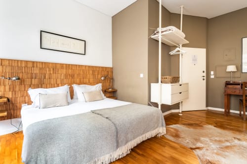 Quarto no hotel PortoSense Porto com cabeceira em madeira, roupa de cama branca, guarda-roupa do chão ao teto e assoalho em madeira
