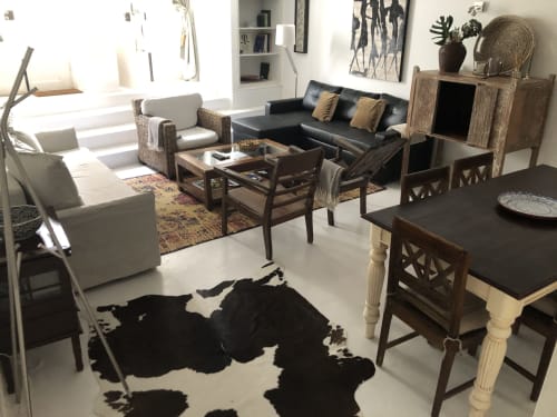 Lounge do hotel PortoSense com tapete de couro estampado preto e branco, sofá de couro escuro, cadeiras trançadas e mesa de jantar em madeira