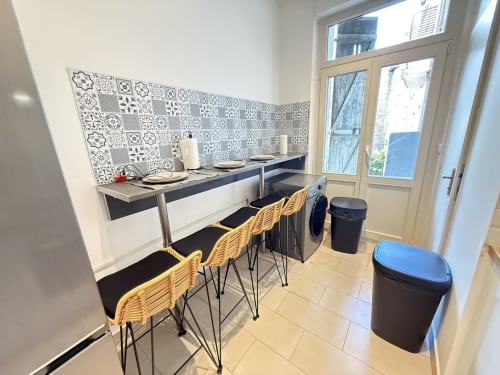 Cuisine-séjour moderne dans un appartement à Metz avec carrelage motifs, bar, et portes-fenêtres sur balcon