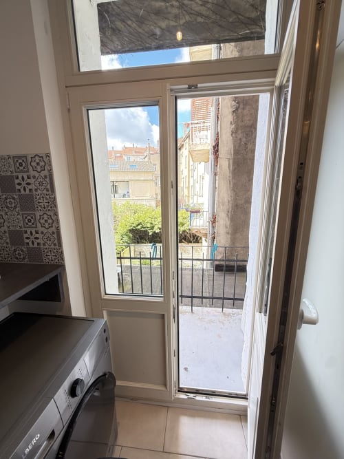 Cuisine avec portes-fenêtres donnant sur un balcon avec vue sur les bâtiments et la verdure de Metz