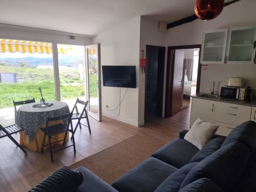 Sala de estar da Casa Do Refúgio com sofá, mesa de jantar, TV, cozinha e vistas para a serra em Covilhã