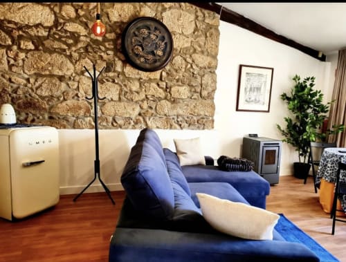 Sala moderna da Casa Do Refúgio em Covilhã com sofá azul, parede de pedra e decoração vintage