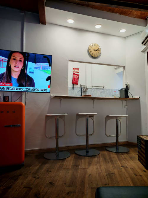 Moderna recepção do hotel Casa Do Refúgio em Covilhã com bar, geladeira vermelha e relógio de parede