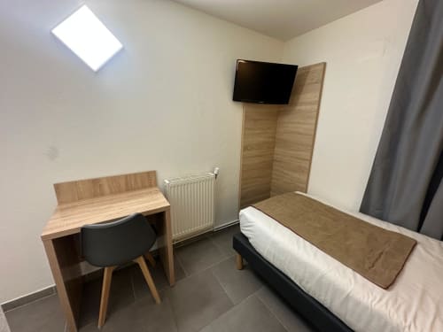 Budget room at Hôtel Norotel Brumath with bed, desk, TV, and heating radiator in Brumath