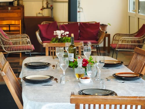 Table élégante dressée pour le dîner à La Kaz 57 avec vin, fleurs et chaises en rotin à La Plaine des Palmistes