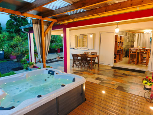 Espace spa luxueux à La Kaz 57 avec bain à remous illuminé, terrasse en bois et coin repas à La Plaine des Palmistes