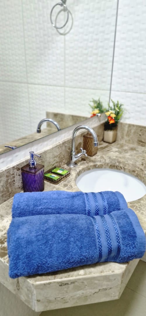 Modern bathroom sink at Praieira Pousada with blue towels, soap dispenser, and white round sink in Itacaré hostel