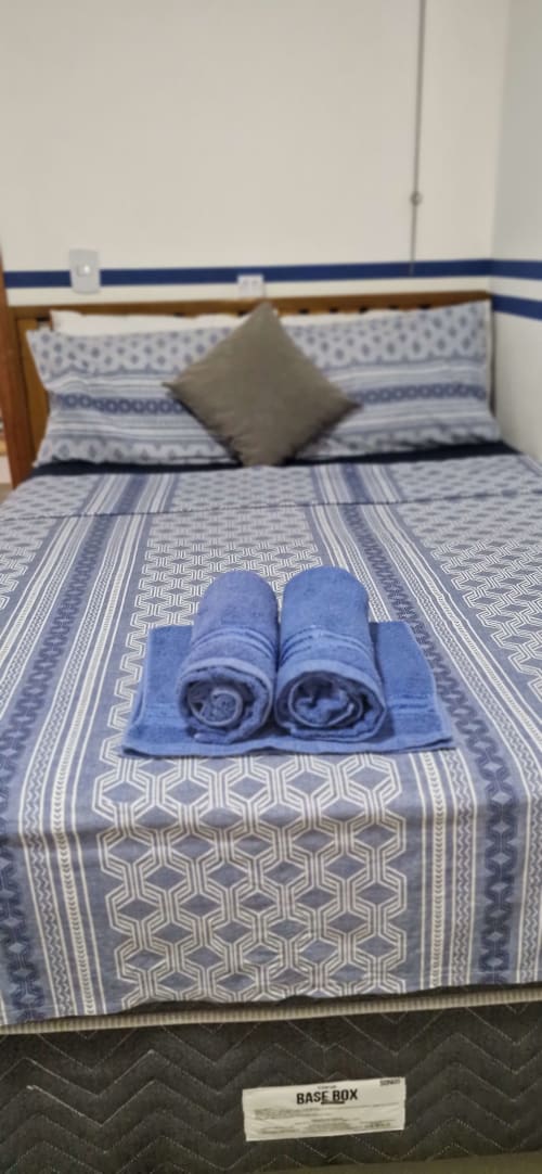 Blue and white patterned bed with rolled towels at Praireira Pousada&Hostel in Itacaré