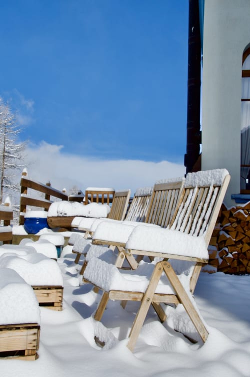Chaises longues en bois enneigées sur la terrasse de l'Hôtel De La Sage avec vue alpine à La Sage, Suisse