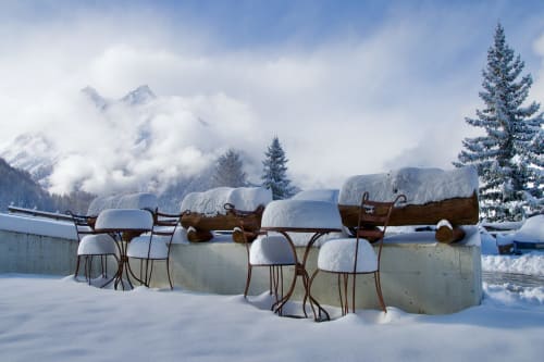 Espace assis extérieur enneigé de l'Hôtel De La Sage à La Sage, Suisse, avec montagnes alpines et sapins en arrière-plan.