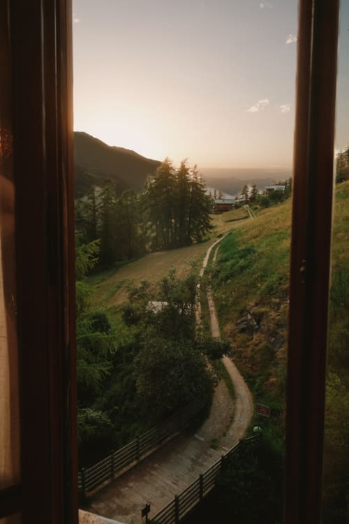 Vue de la vallée montagnarde depuis la fenêtre de l'Hôtel De La Sage, La Sage Suisse, avec sentier sinueux et forêt