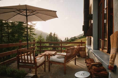 Terrasse de l'Hôtel De La Sage avec chaises en bois, parasol et vue sur les montagnes de La Sage, Suisse