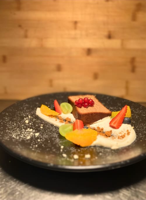 Plateau de desserts gourmands à l'Hôtel De La Sage : gâteau au chocolat, baies et fruits frais sur assiette noire