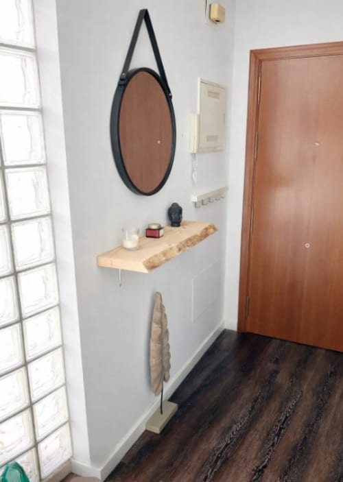 Espejo moderno con marco negro y repisa de madera en la entrada del apartamento Living Sur, Sanlúcar de Barrameda