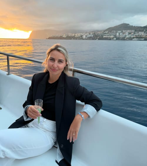 Woman enjoying sunset on yacht near Ribeira Brava, Madeira with coastal town backdrop