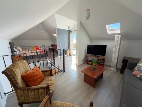 Spacious loft bedroom at Check Madeira hotel in Ribeira Brava with sloped ceilings, skylight, TV area, and modern amenities