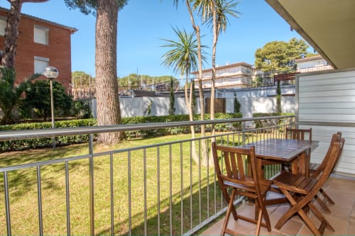 Ground floor apartment patio with garden view, wooden furniture, and palm trees in Palafrugell