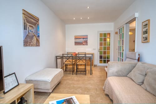 Ground floor apartment living area in Palafrugell with sofa, dining table, and garden view artwork on walls
