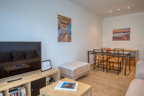 Modern apartment living room in Palafrugell with TV, dining area, and coastal artwork decor