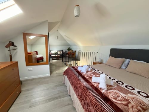 Modern attic bedroom at Check Madeira, Ribeira Brava with sloped ceilings, wooden furniture, and contemporary décor