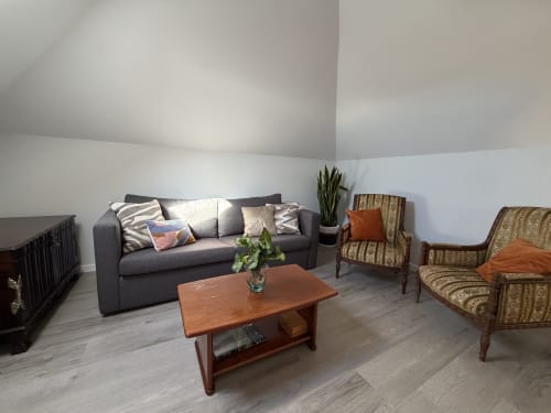 Modern living room at Check Madeira hotel in Ribeira Brava with gray sofa, wooden table, and patterned armchairs.