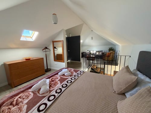 Spacious attic bedroom at Check Madeira hotel in Ribeira Brava with skylights, wooden dresser, and mezzanine loft area