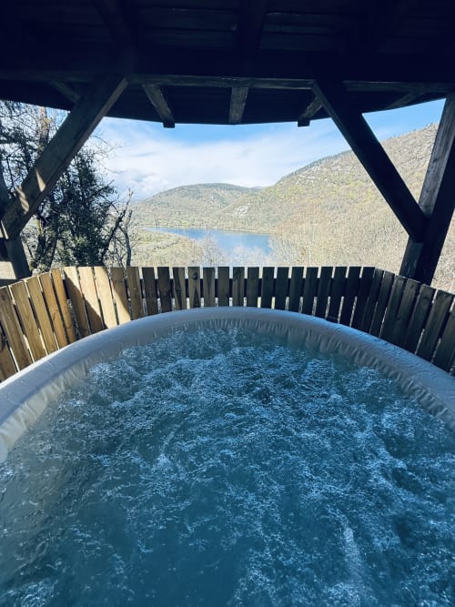 Baignoire à bulles avec vue sur un lac forestier et les montagnes aux Cabanes du Belvédère, Serrières-sur-Ain