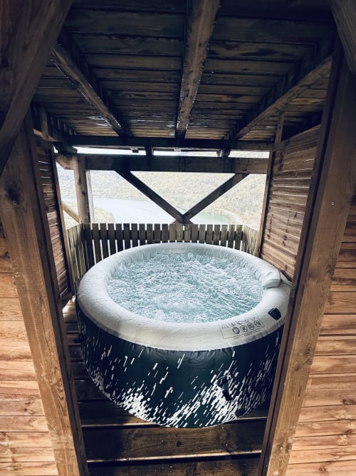 Bubbling hot tub on wooden deck with lake view at Cabanes du Belvédère spa villa, Serrières-sur-Ain