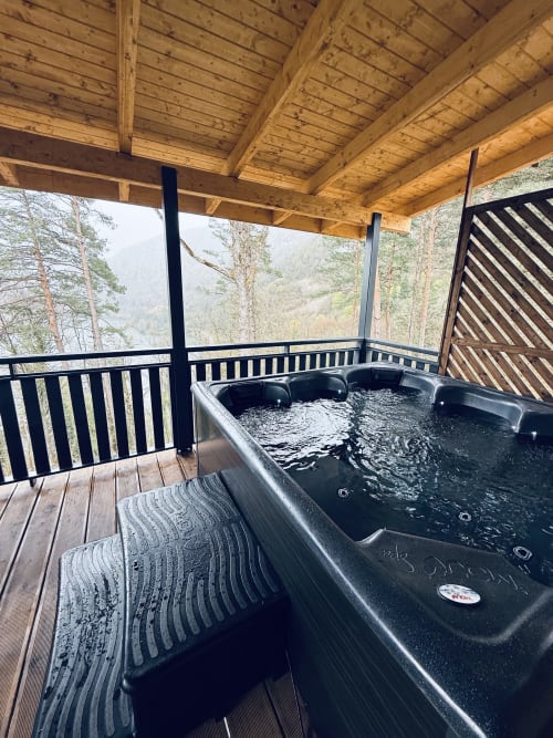 Bain à remous sur terrasse en bois avec vue sur la montagne et la rivière au Lodge l'ORCHIDÉE, Serrières-sur-Ain