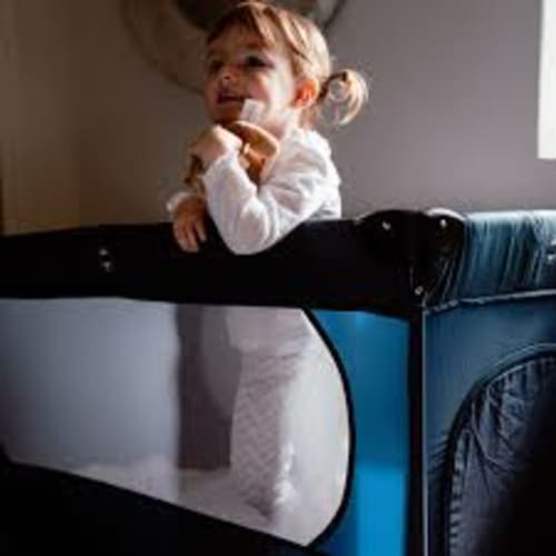 Jeune enfant debout dans un lit parapluie bleu à l'hôtel Douce Nuits à Nuits-Saint-Georges