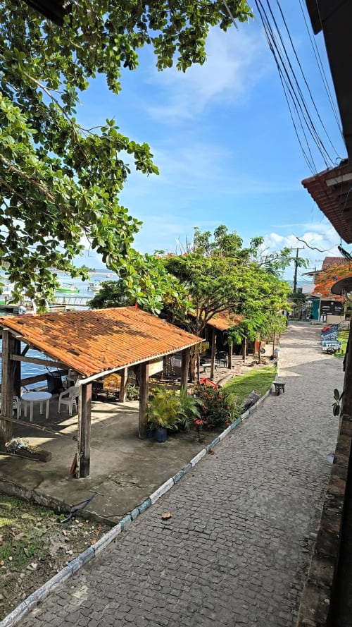 Rustic beachfront terrace at Casa do Porto with wooden shelter, sea view, and tropical vegetation in Boipeba