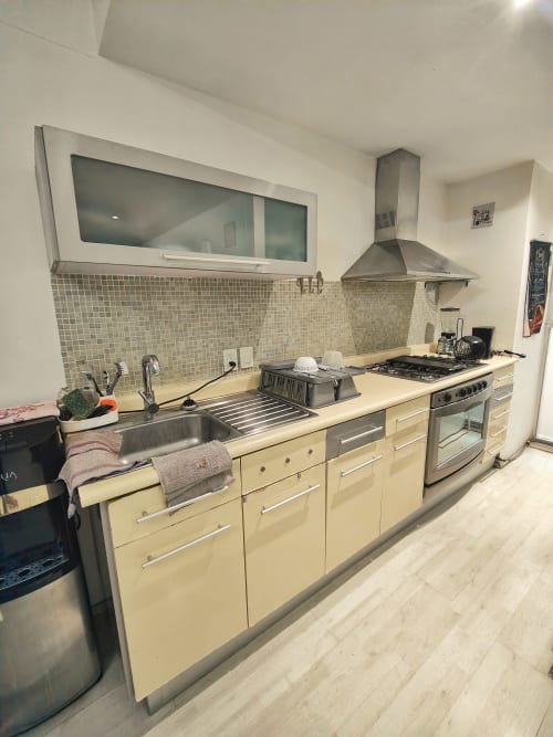 Cocina moderna en apartamento de Capital Park Condos, Ciudad de México, con gabinetes color crema, electrodomésticos de acero inoxidable y piso de azulejos