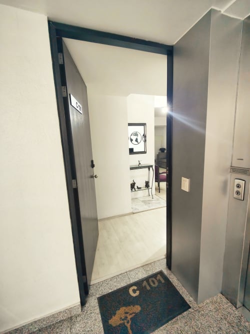Entrada moderna del departamento en Capital Park Condos, Condesa/Roma, Ciudad de México con puerta abierta y vista de la ciudad