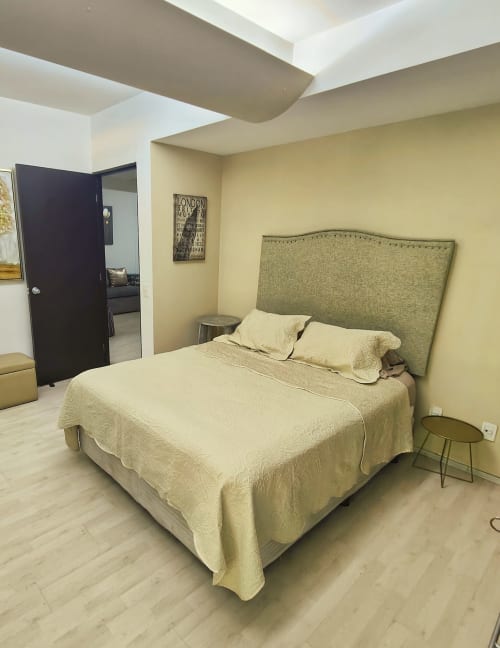 Recámara moderna en Capital Park Condos, Condesa/Roma, Ciudad de México con cama queen, cabecera verde, ropa de cama crema y