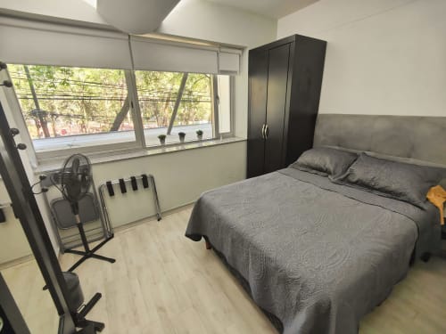 Recámara moderna en Capital Park Condos, Condesa/Roma, Ciudad de México con cama queen, armario negro y vistas de la ciudad