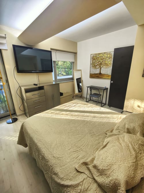 Moderna habitación del condominio Capital Park, Condesa/Roma, CDMX con cama, TV, vista por ventana y diseño contemporáneo