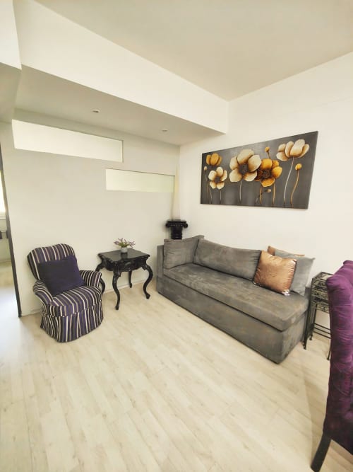 Sala moderna en Capital Park Condos, apartamento Condesa con sofá gris, silla rayada y arte floral dorado en la pared