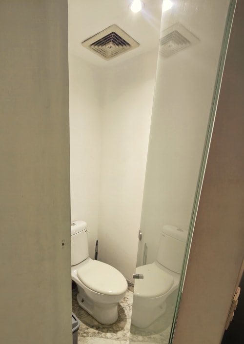 Baño moderno en apartamento Capital Park Condos Ciudad de México con inodoro blanco, lavamanos, extractor de aire y piso de azulejos